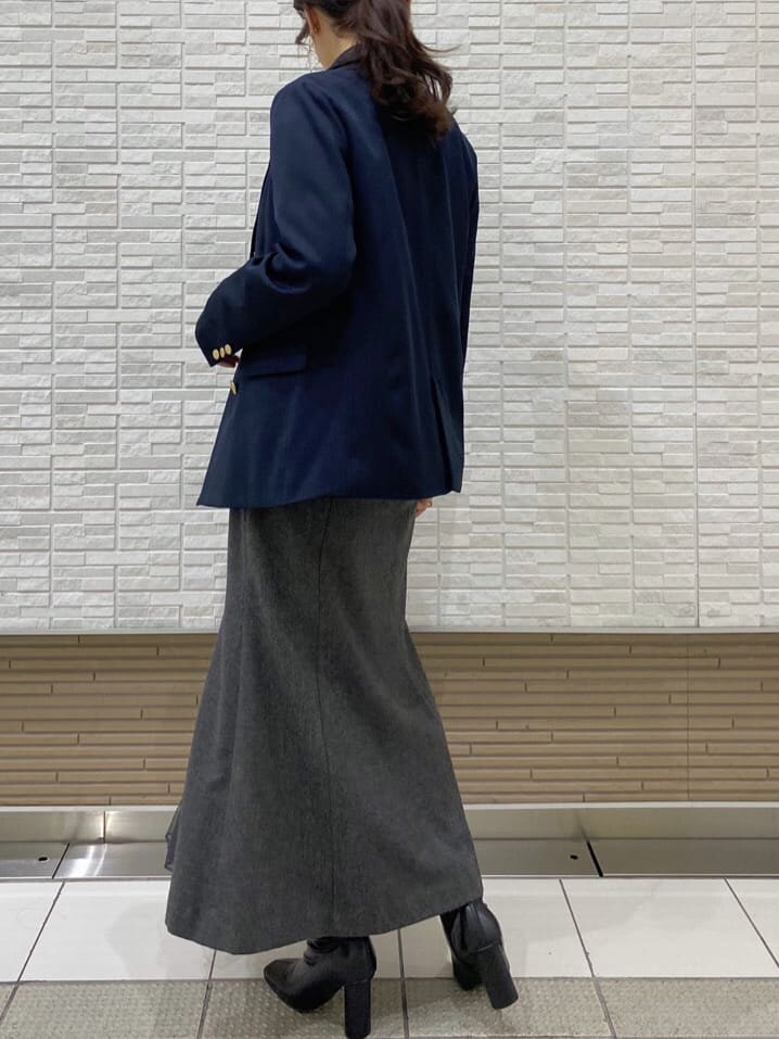 ブラック系のブーツ、ブルー系のテーラードジャケット、グレー系のスカートを着用したレディースの秋コーディネートの5枚目の写真