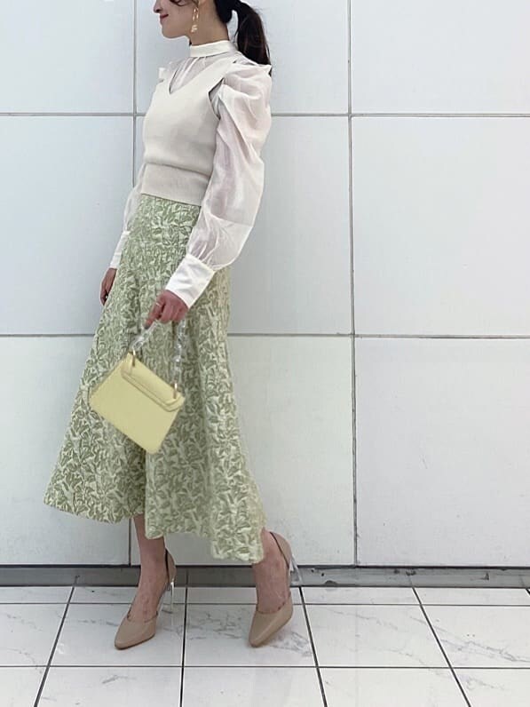 ベージュ系のパンプス、グリーン系のスカート、イエロー系のショルダーバッグを着用したレディースの冬コーディネートの3枚目の写真