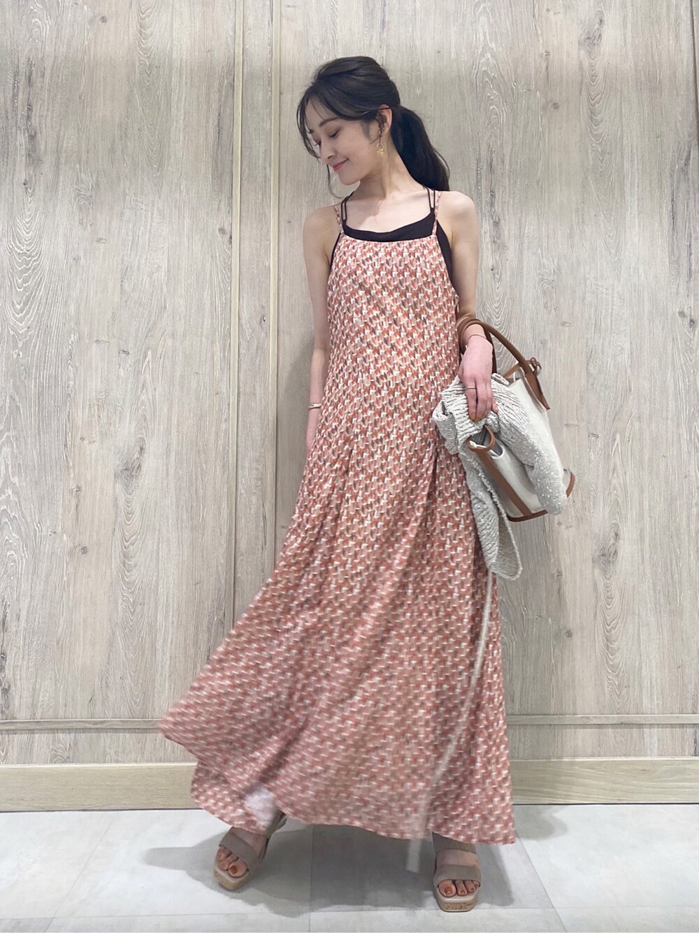 ブラウン系のトートバッグ、ベージュ系のカーディガン/ボレロ、オレンジ系のワンピースを着用したレディースの春コーディネートの7枚目の写真