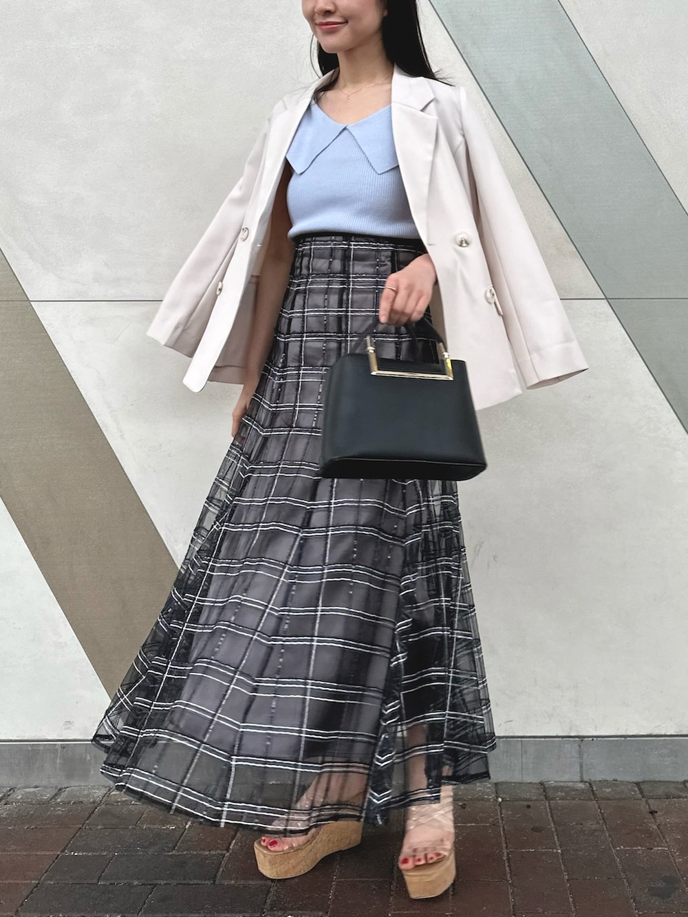 ブラック系のハンドバッグ、ブラック系のスカート、その他のサンダルを着用したレディースの春コーディネートの2枚目の写真