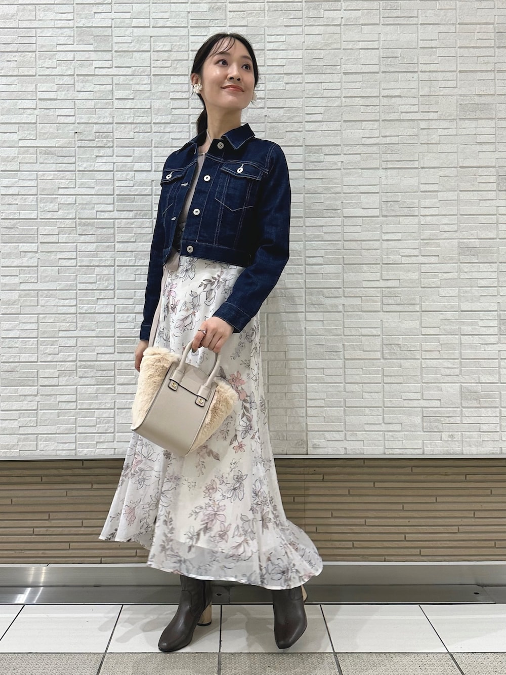 ブラウン系のブーツ、ホワイト系のハンドバッグ、ブルー系のデニムジャケットを着用したレディースの夏コーディネートの2枚目の写真