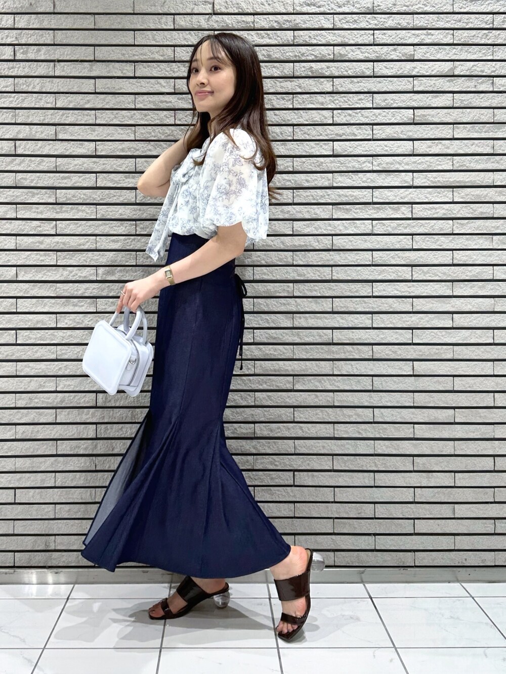 ブルー系のハンドバッグ、ブルー系のスカート、ブルー系のシャツ/ブラウスを着用したレディースの夏コーディネートの3枚目の写真