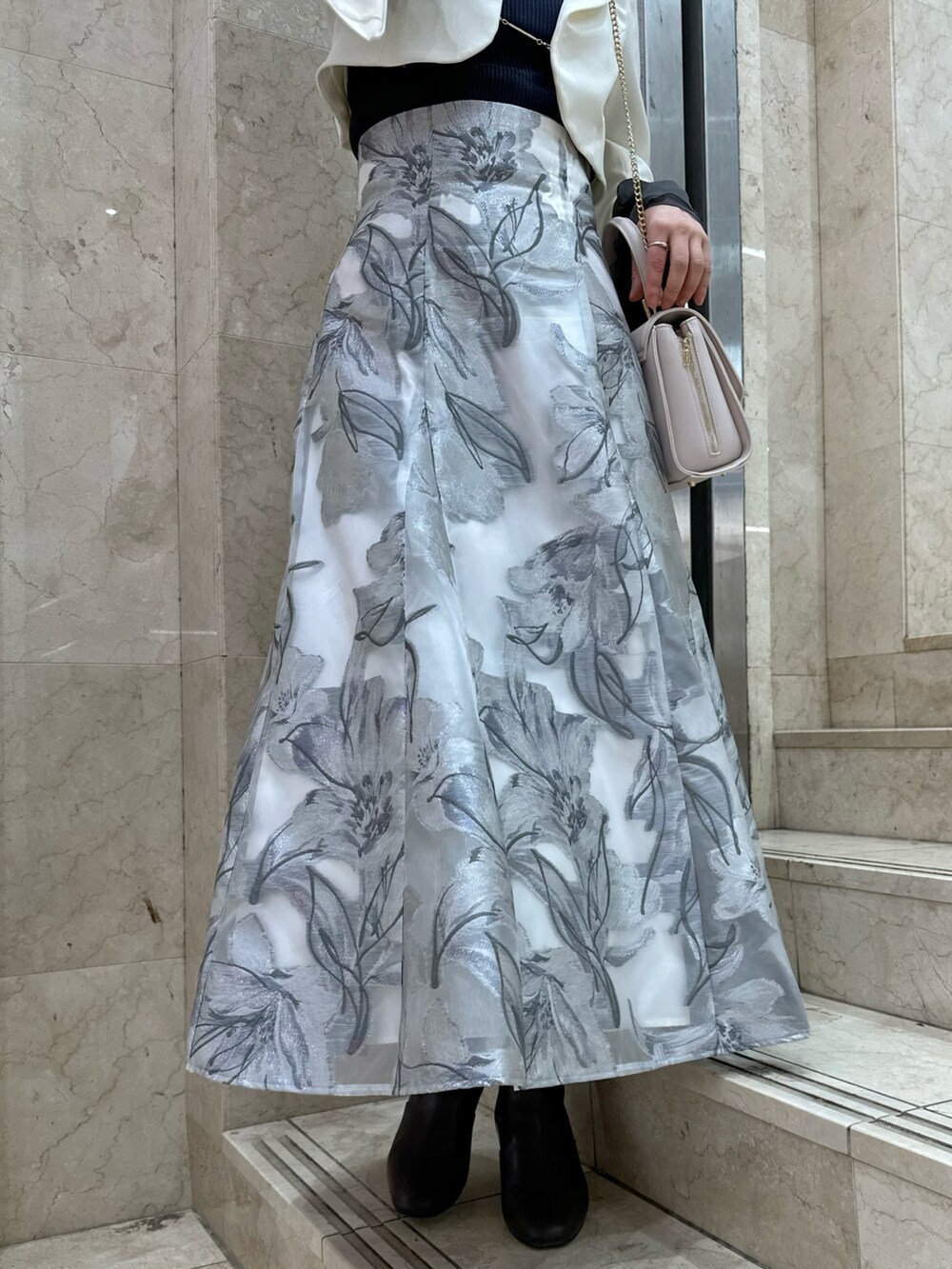 ホワイト系のテーラードジャケット、グレー系のスカート、グレー系のニット/セーターを着用したレディースの春コーディネートの9枚目の写真