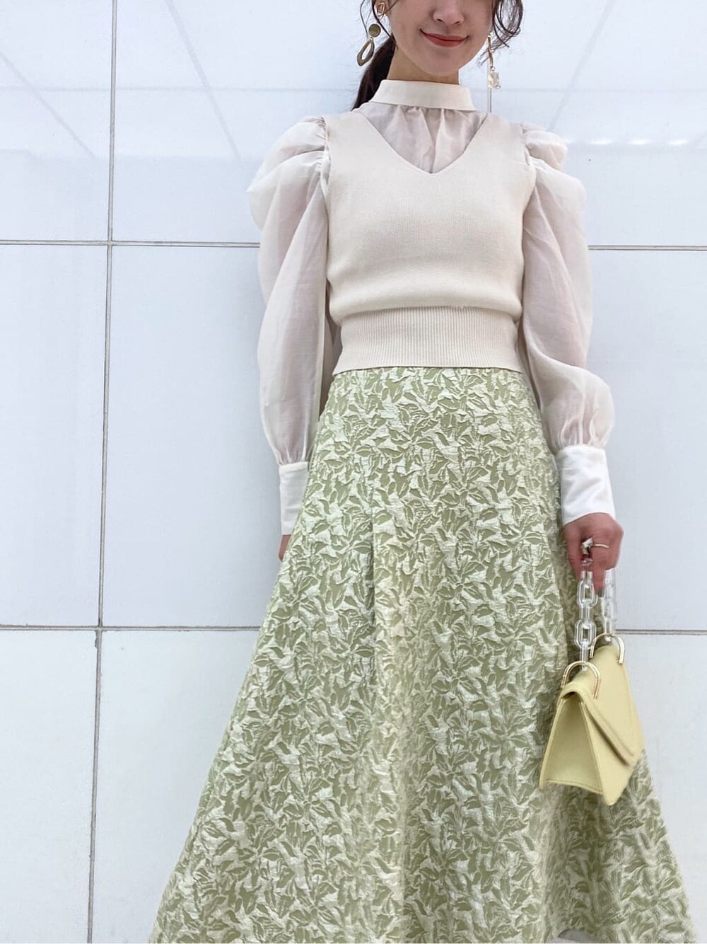 ベージュ系のパンプス、グリーン系のスカート、イエロー系のショルダーバッグを着用したレディースの冬コーディネートの5枚目の写真