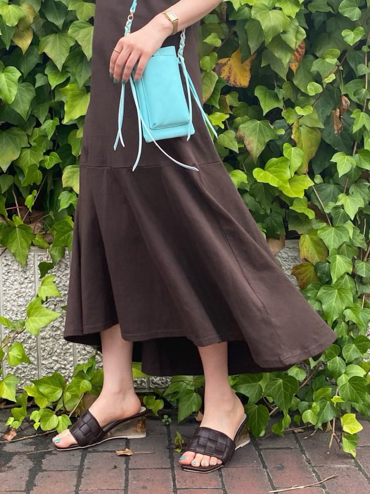 グリーン系のショルダーバッグ、ブラウン系のサンダル、ベージュ系のキャミソールを着用したレディースの夏コーディネートの3枚目の写真