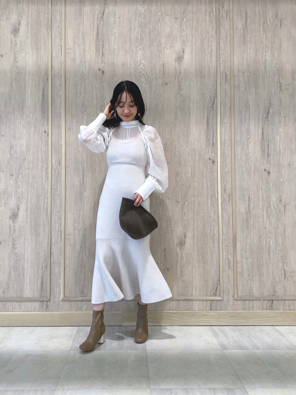 ベージュ系のブーツ、ホワイト系のワンピース、ホワイト系のチューブトップを着用したレディースの冬コーディネートの3枚目の写真