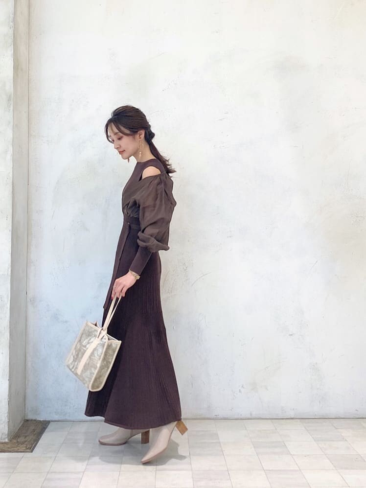 ベージュ系のハンドバッグ、ベージュ系のブーツ、ブラウン系のワンピースを着用したレディースの秋コーディネートの3枚目の写真