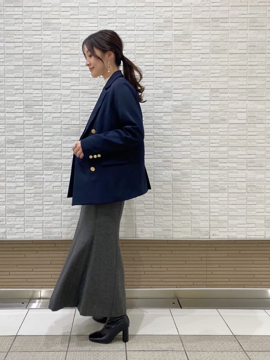ブラック系のブーツ、ブルー系のテーラードジャケット、グレー系のスカートを着用したレディースの秋コーディネートの4枚目の写真