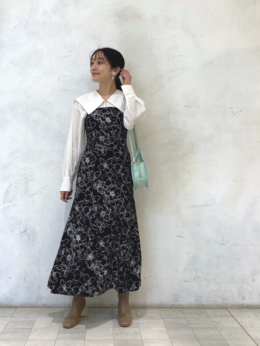 ベージュ系のブーツ、グリーン系のハンドバッグ、その他のワンピースを着用したレディースの冬コーディネートの2枚目の写真