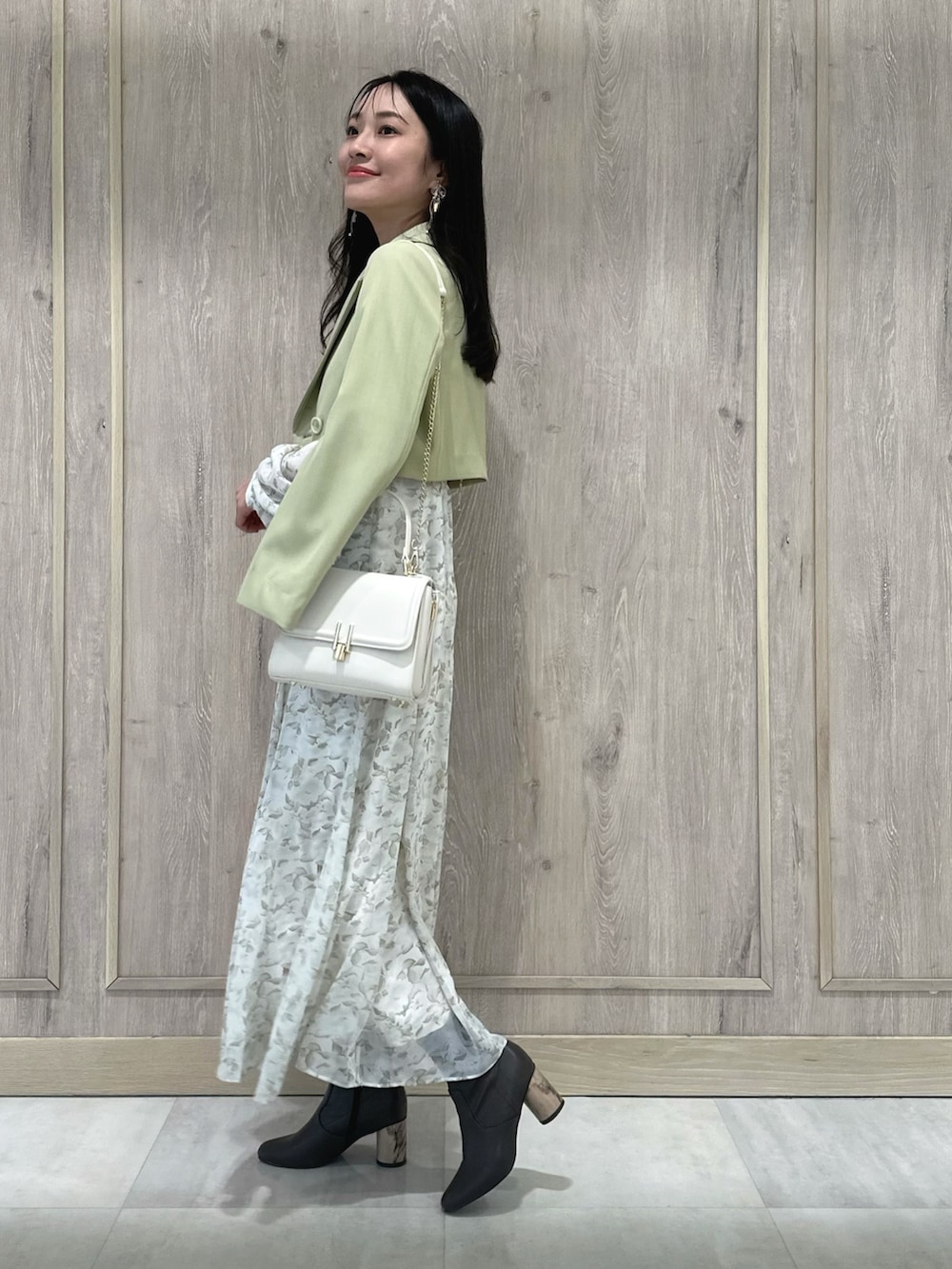 ホワイト系のハンドバッグ、ブラウン系のブーツ、グリーン系のテーラードジャケットを着用したレディースの冬コーディネートの3枚目の写真