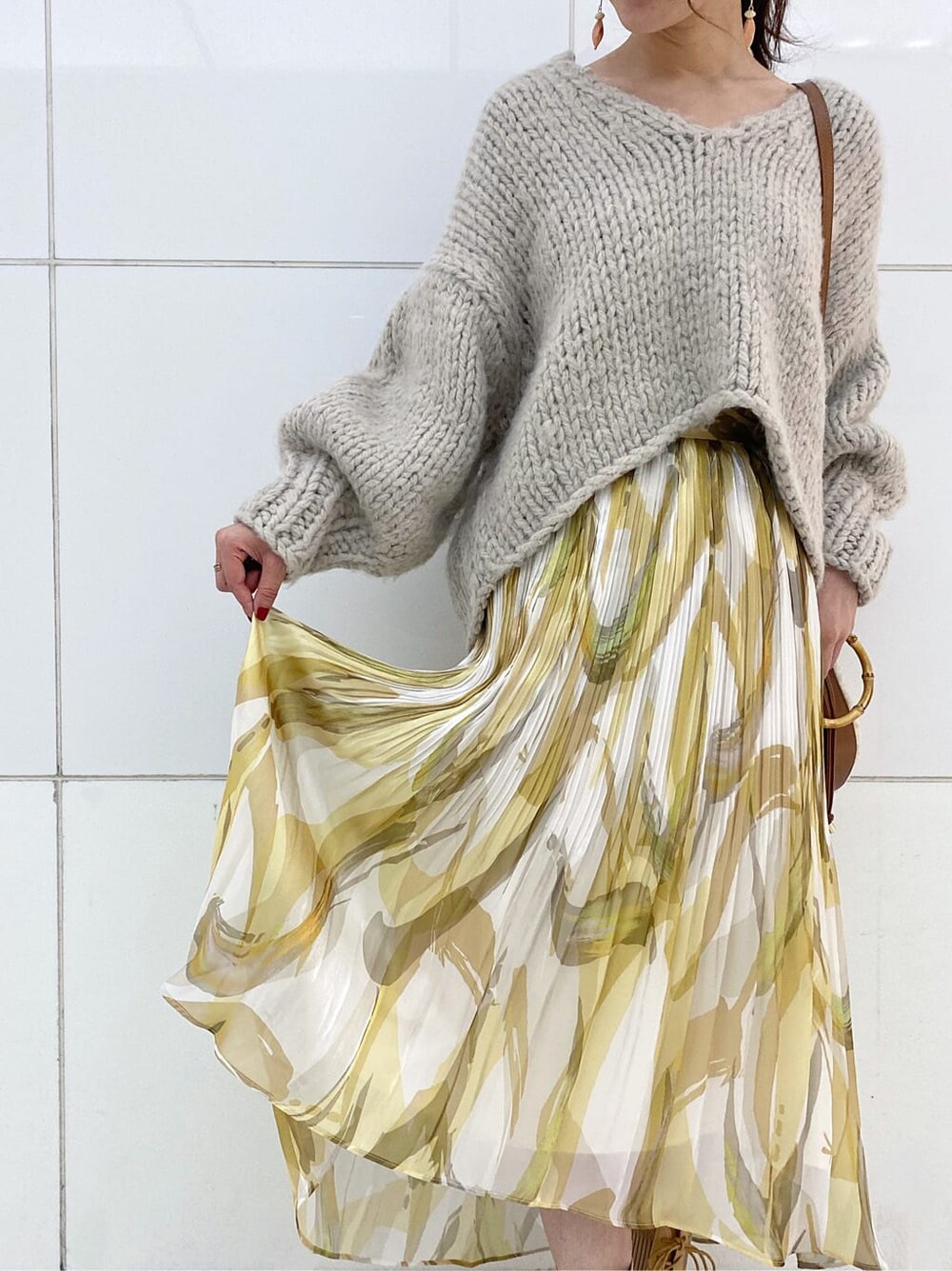 イエロー系のスカート、グレー系のニット/セーター、ベージュ系のブーツを着用したレディースの秋コーディネートの5枚目の写真