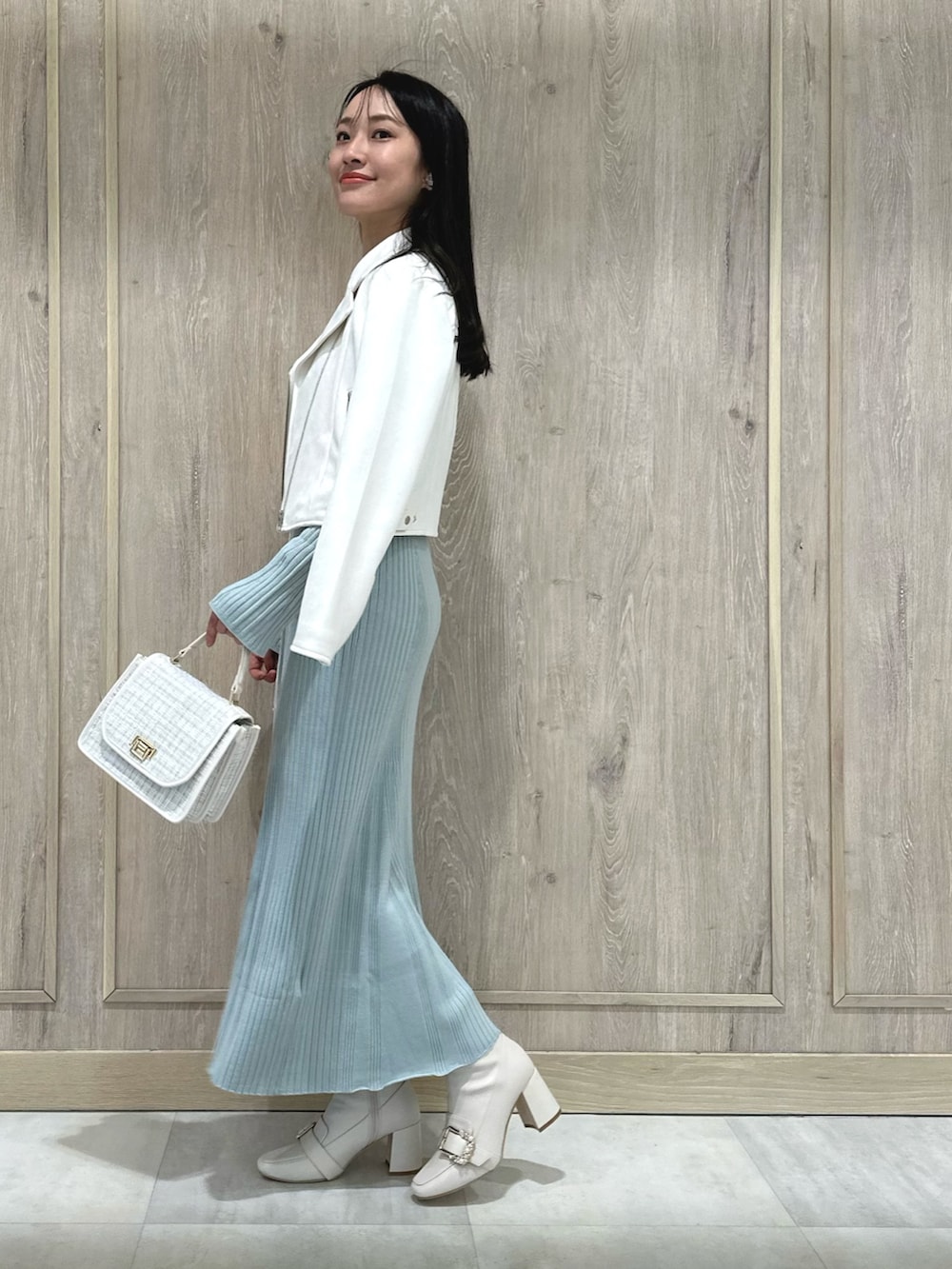 ホワイト系のハンドバッグ、ホワイト系のブーツ、ブルー系のワンピースを着用したレディースの冬コーディネートの3枚目の写真