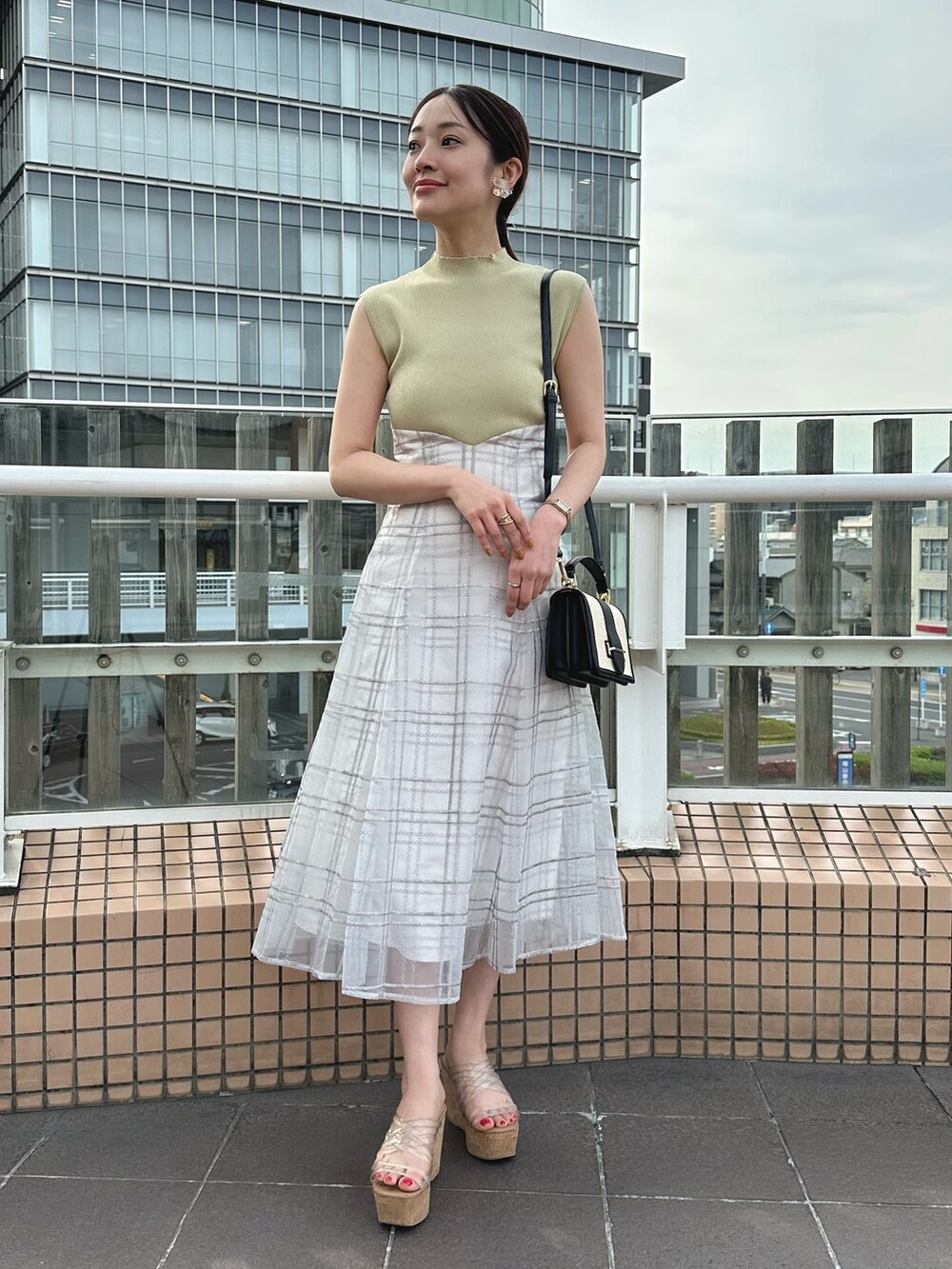 その他のサンダル、ブラック系のハンドバッグ、グリーン系のワンピースを着用したレディースの春コーディネートの2枚目の写真