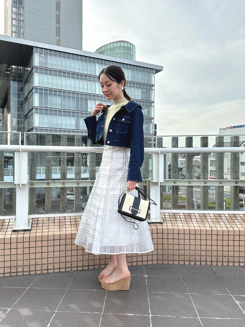 ホワイト系のハンドバッグ、グリーン系のワンピース、ブルー系のデニムジャケットを着用したレディースの春コーディネートの2枚目の写真