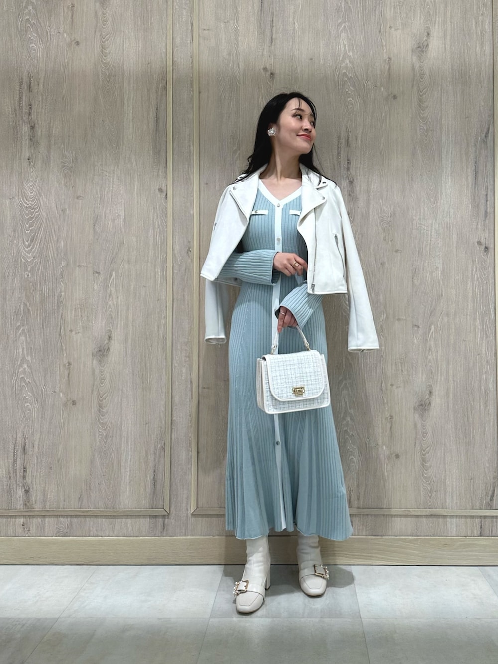 ホワイト系のハンドバッグ、ホワイト系のブーツ、ブルー系のワンピースを着用したレディースの冬コーディネートの2枚目の写真