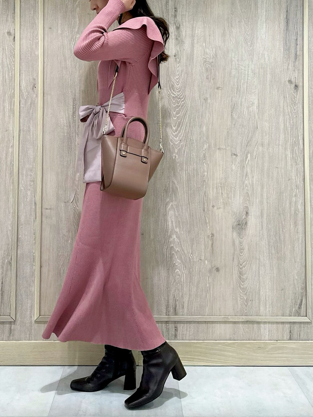 ピンク系のワンピース、ブラウン系のハンドバッグ、ブラウン系のブーツを着用したレディースの冬コーディネートの3枚目の写真