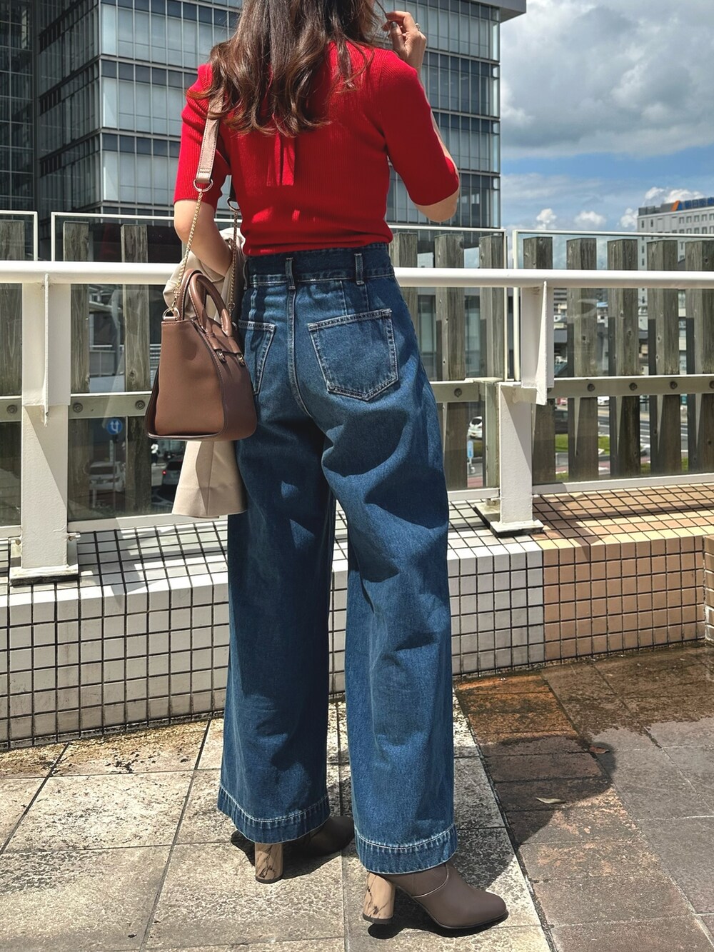 レッド系のニット/セーター、ブルー系のデニムパンツ、ブラウン系のブーツを着用したレディースの夏コーディネートの4枚目の写真