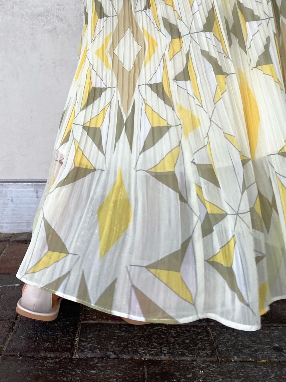 ブラウン系のトートバッグ、ベージュ系のサンダル、イエロー系のスカートを着用したレディースの夏コーディネートの8枚目の写真