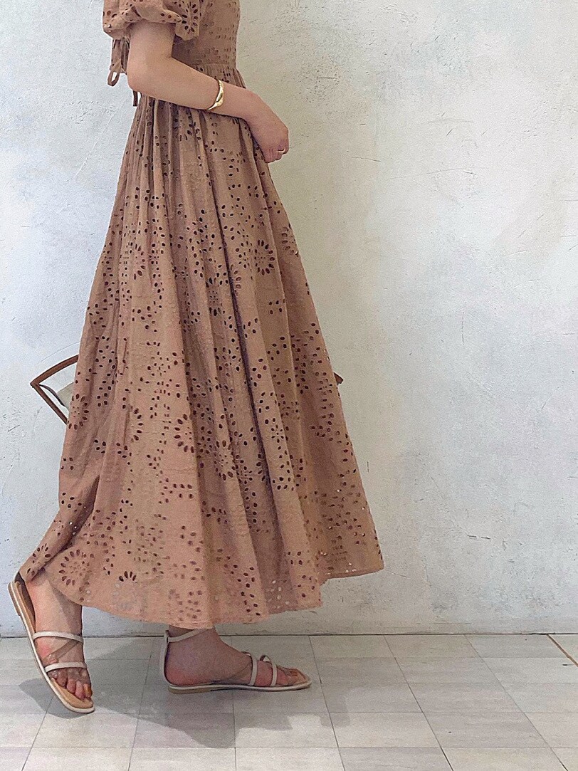 ブラウン系のトートバッグ、ベージュ系のワンピース、ベージュ系のサンダルを着用したレディースの春コーディネートの2枚目の写真