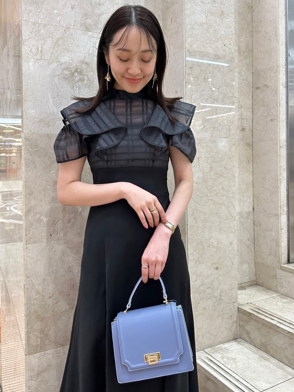 ブラック系のワンピース、ブルー系のハンドバッグ、その他のサンダルを着用したレディースの春コーディネートの5枚目の写真