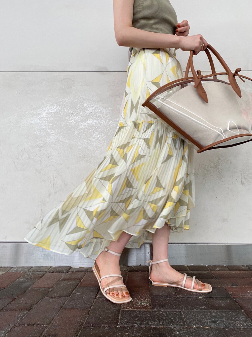 ブラウン系のトートバッグ、ベージュ系のサンダル、イエロー系のスカートを着用したレディースの夏コーディネートの3枚目の写真