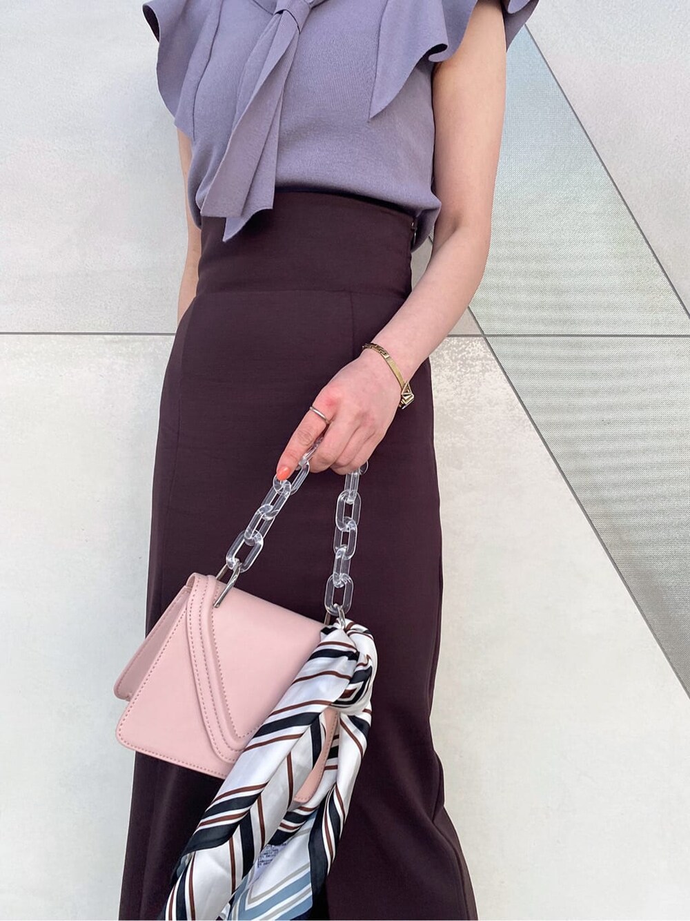 ピンク系のショルダーバッグ、グレー系のニット/セーター、ブラウン系のスカートを着用したレディースの春コーディネートの6枚目の写真