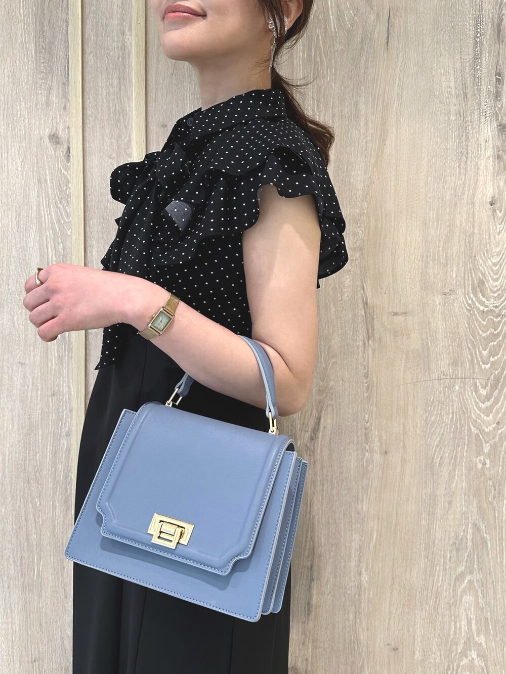 ブラック系のワンピース、ブルー系のハンドバッグ、シルバー系のサンダルを着用したレディースの春コーディネートの4枚目の写真