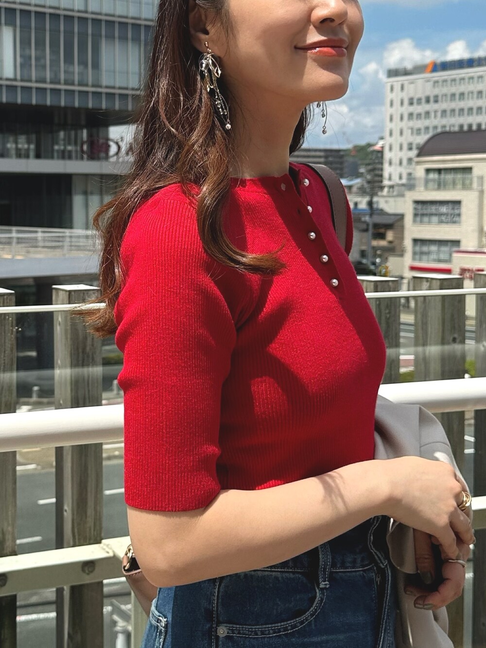 レッド系のニット/セーター、ブルー系のデニムパンツ、ブラウン系のブーツを着用したレディースの夏コーディネートの6枚目の写真