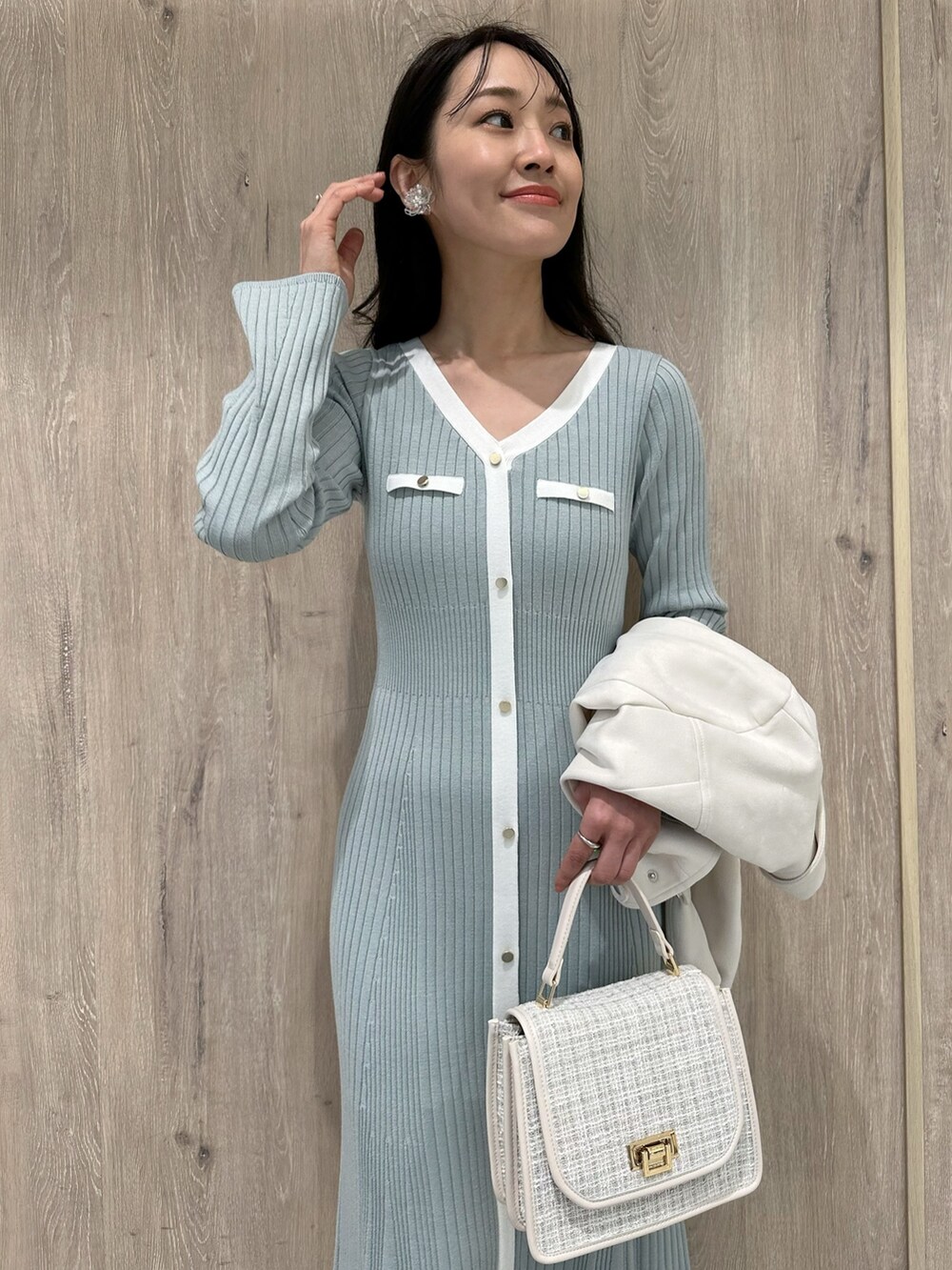 ホワイト系のハンドバッグ、ホワイト系のブーツ、ブルー系のワンピースを着用したレディースの冬コーディネートの6枚目の写真