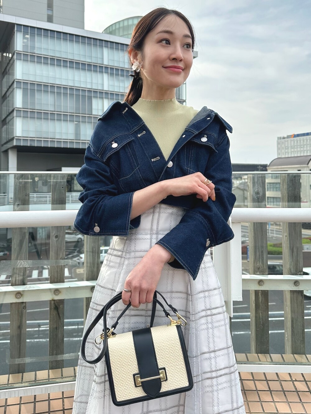 ホワイト系のハンドバッグ、グリーン系のワンピース、ブルー系のデニムジャケットを着用したレディースの春コーディネートの5枚目の写真