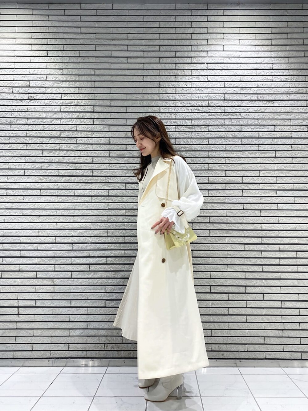 ホワイト系のその他アウター、イエロー系のショルダーバッグ、ベージュ系のワンピースを着用したレディースの冬コーディネートの3枚目の写真