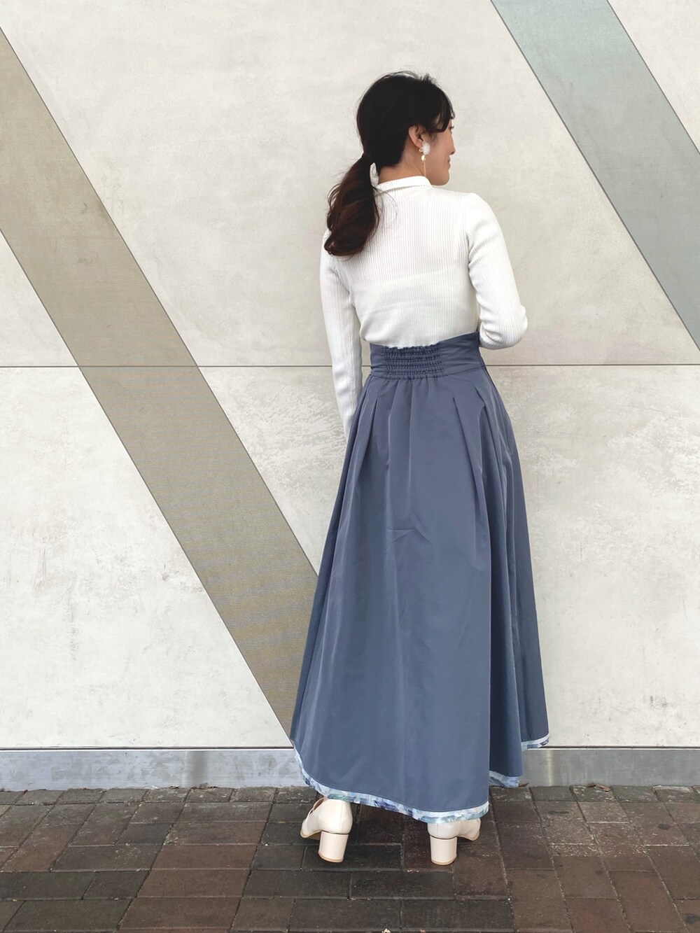 ブルー系のスカート、ホワイト系のニット/セーター、ホワイト系のキャミソールを着用したレディースの冬コーディネートの5枚目の写真