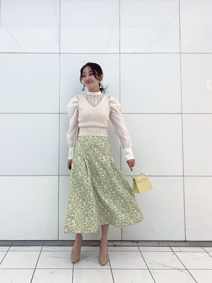 ベージュ系のパンプス、グリーン系のスカート、イエロー系のショルダーバッグを着用したレディースの冬コーディネートの2枚目の写真