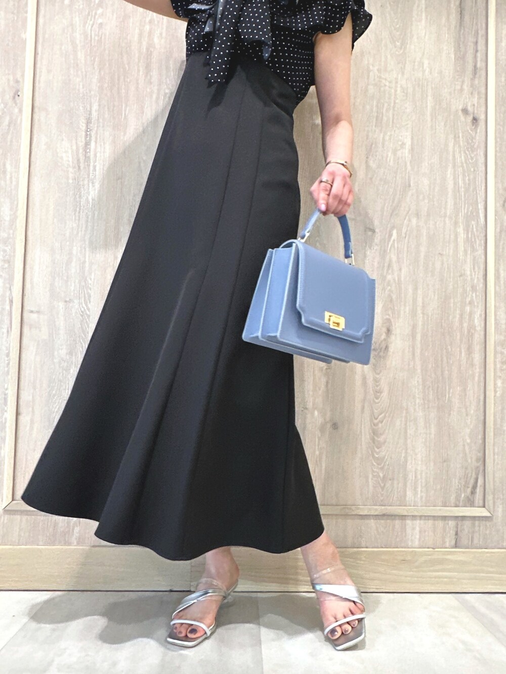ブラック系のワンピース、ブルー系のハンドバッグ、シルバー系のサンダルを着用したレディースの春コーディネートの6枚目の写真