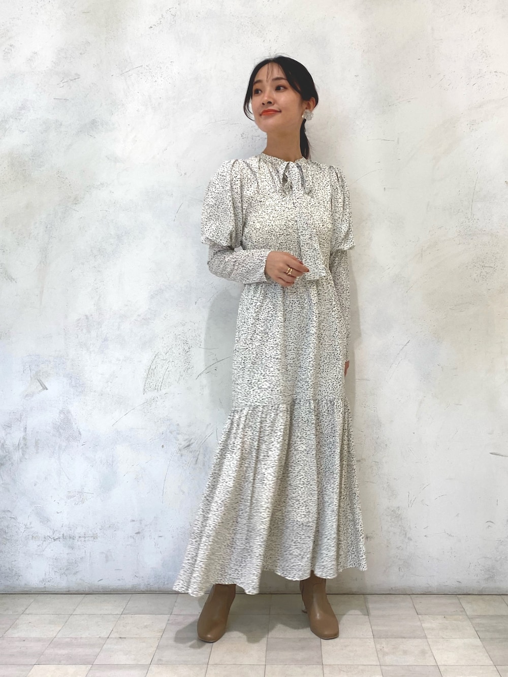 ホワイト系のワンピース、ベージュ系のブーツ、シルバー系のイヤリングを着用したレディースの秋コーディネートの2枚目の写真