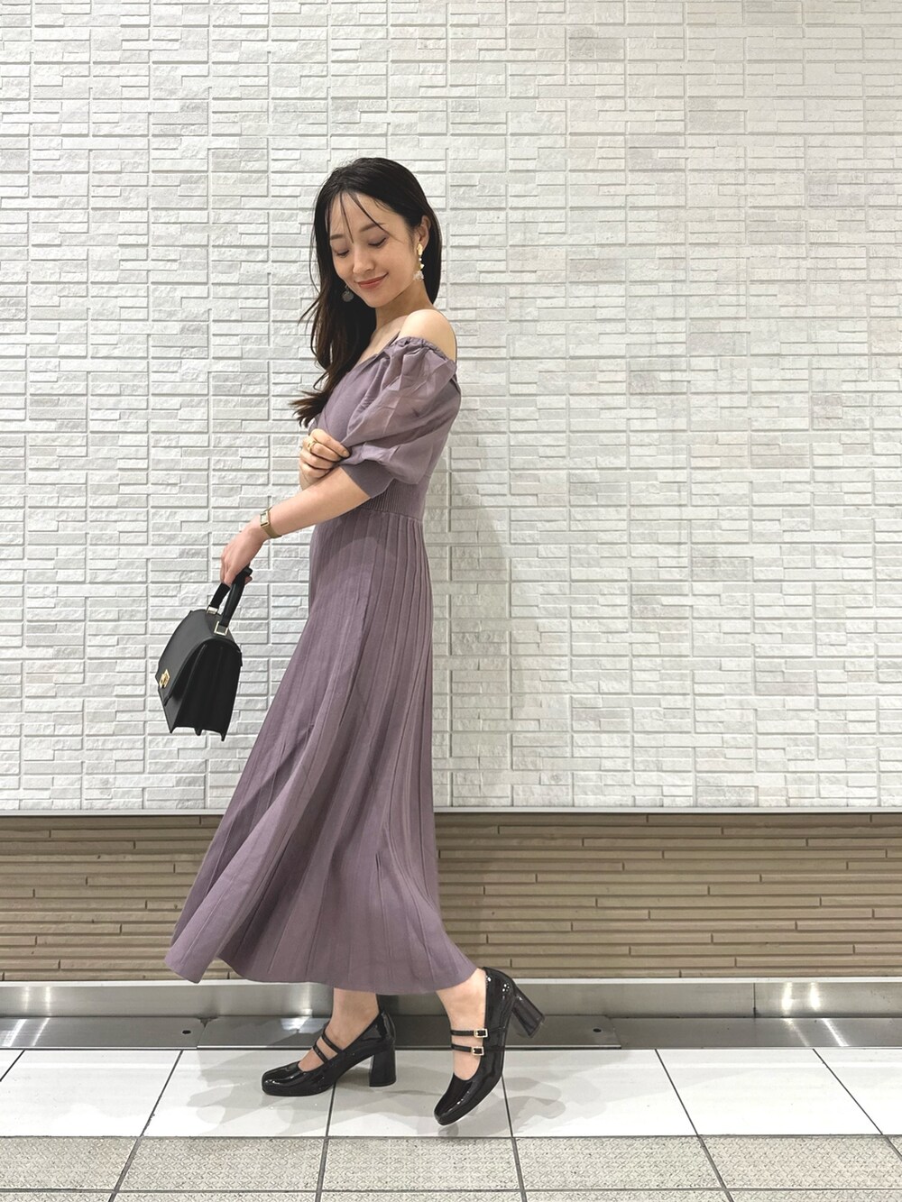 ブラウン系のパンプス、ブラック系のハンドバッグ、パープル系のワンピースを着用したレディースの夏コーディネートの2枚目の写真