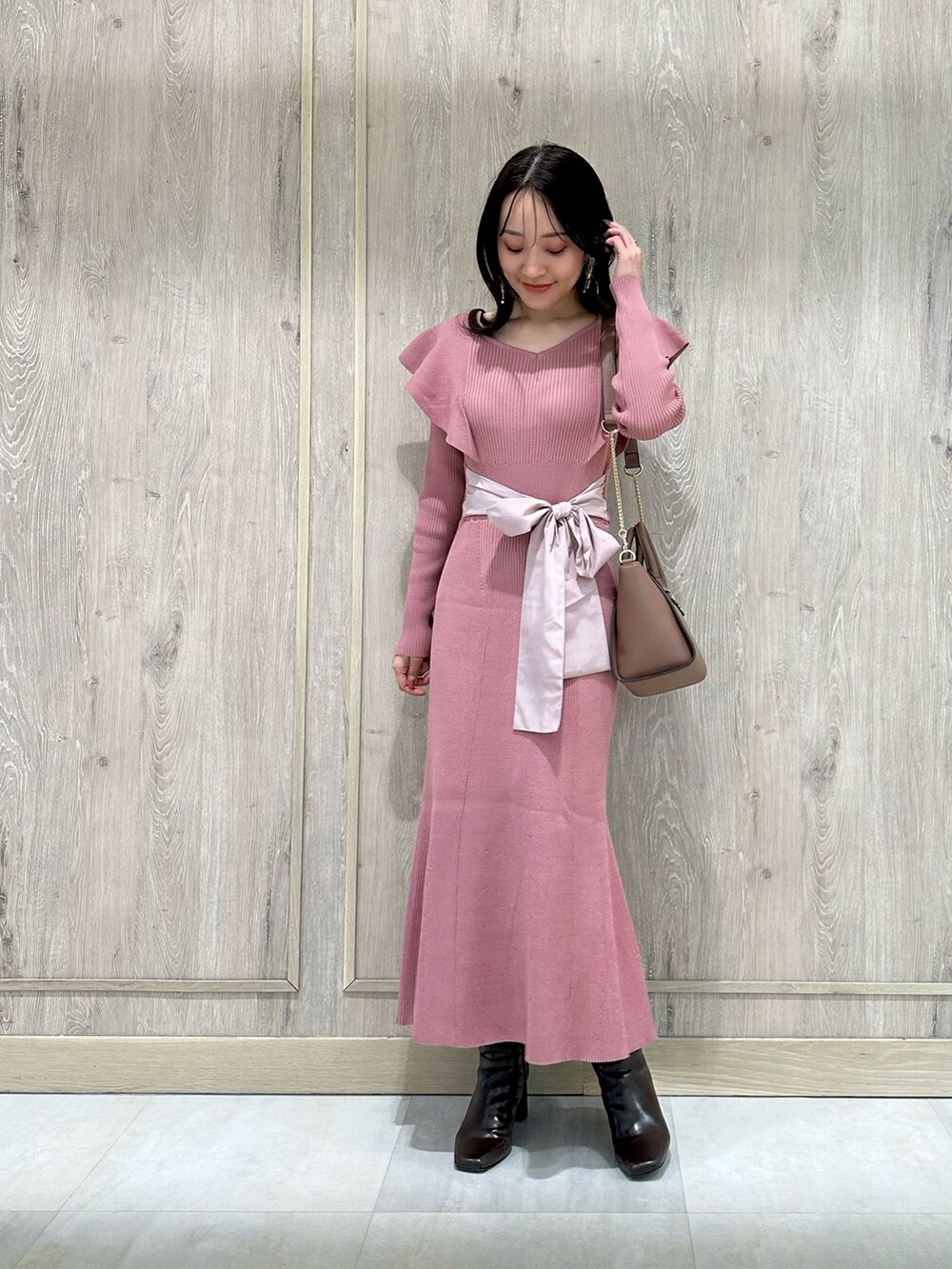 ピンク系のワンピース、ブラウン系のハンドバッグ、ブラウン系のブーツを着用したレディースの冬コーディネートの2枚目の写真