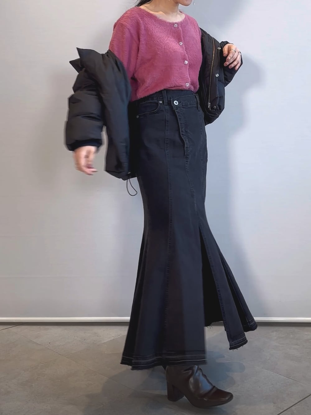 ブラウン系のブーツ、ブラック系のデニムスカート、ブラック系のダウンジャケット/コートを着用したレディースの冬コーディネートの4枚目の写真