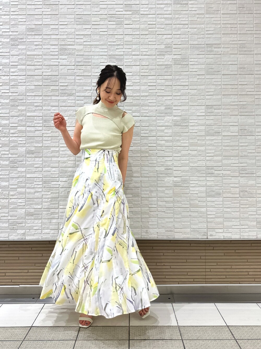 ホワイト系のキャミソール、ホワイト系のサンダル、イエロー系のスカートを着用したレディースの夏コーディネートの2枚目の写真