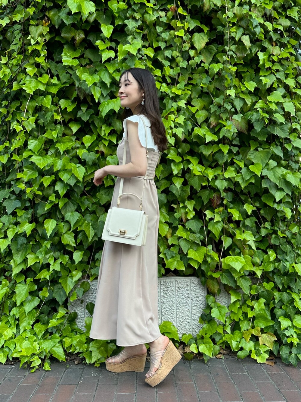 その他のサンダル、ホワイト系のハンドバッグ、ベージュ系のワンピースを着用したレディースの春コーディネートの2枚目の写真