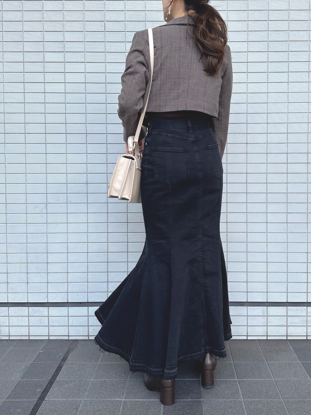 ベージュ系のショルダーバッグ、ブラック系のデニムスカート、ブラウン系のニット/セーターを着用したレディースの秋コーディネートの4枚目の写真