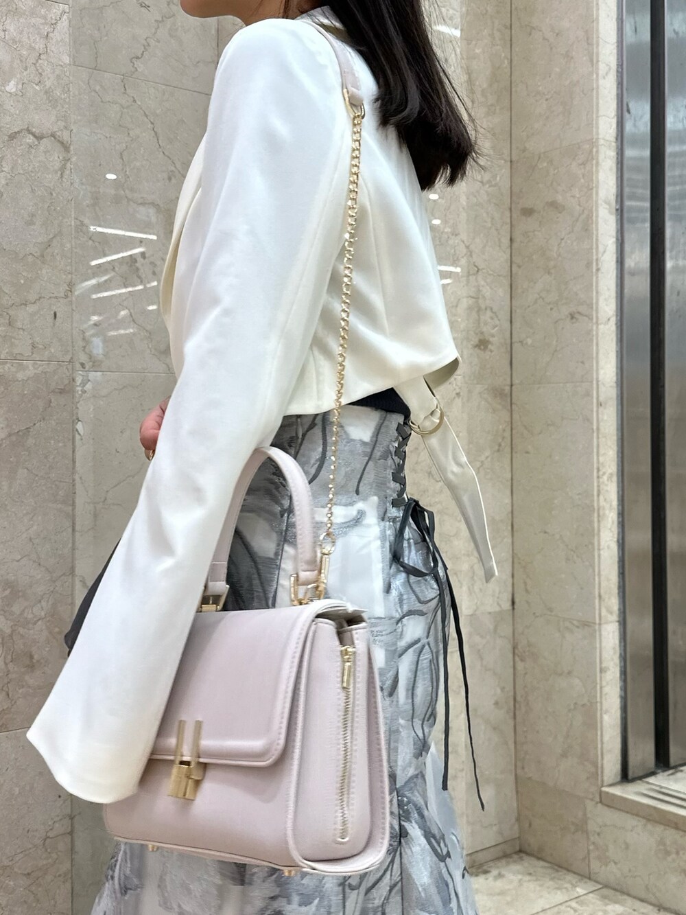 ホワイト系のテーラードジャケット、グレー系のスカート、グレー系のニット/セーターを着用したレディースの春コーディネートの6枚目の写真