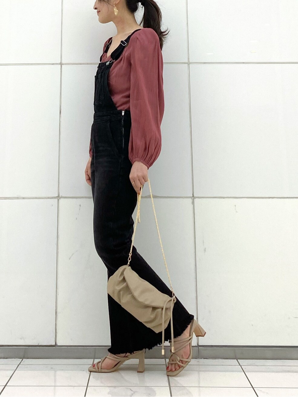 ブラック系のサロペット/オーバーオール、レッド系のシャツ/ブラウス、ベージュ系のサンダルを着用したレディースの春コーディネートの3枚目の写真