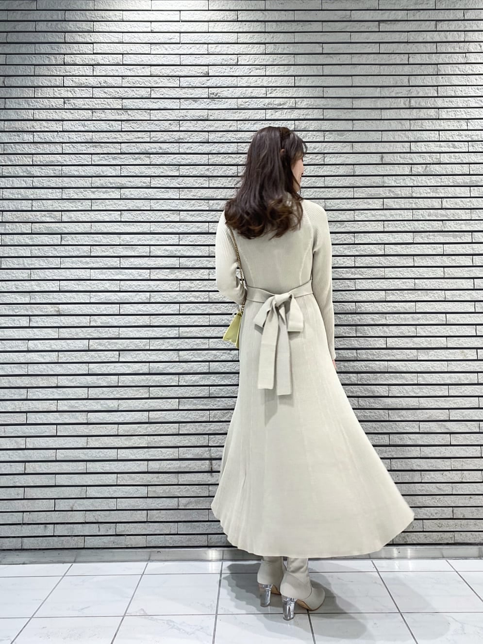 イエロー系のショルダーバッグ、ベージュ系のワンピース、ホワイト系のその他シューズを着用したレディースの冬コーディネートの3枚目の写真