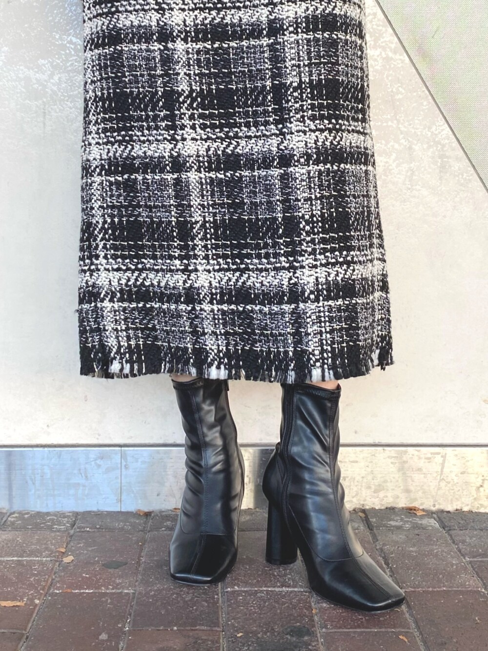 グレー系のニット/セーター、ブラック系のスカート、ブラック系のブーツを着用したレディースの秋コーディネートの7枚目の写真