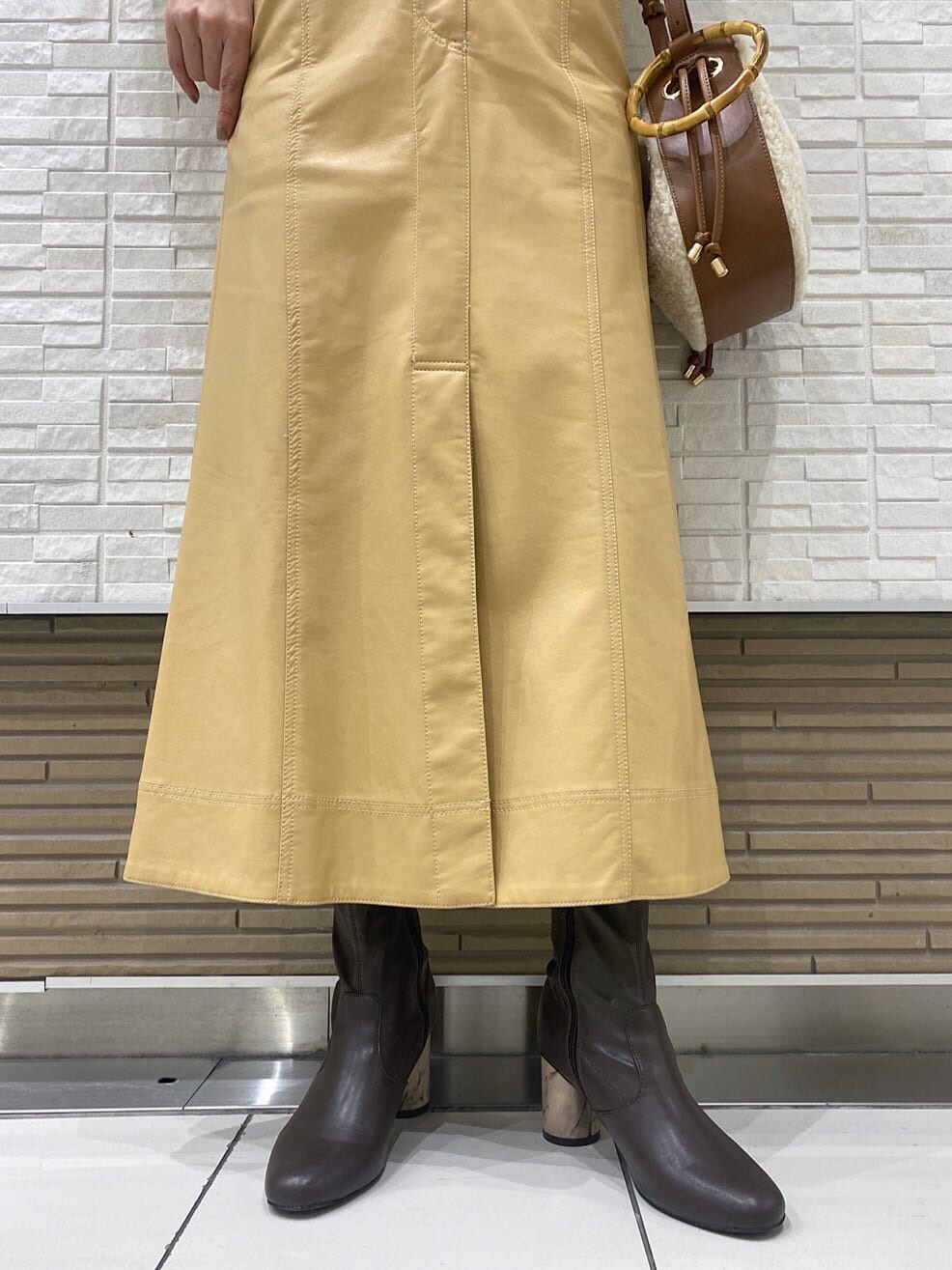 ベージュ系のスカート、ブラウン系のブルゾン、ブラウン系のハンドバッグを着用したレディースの冬コーディネートの8枚目の写真