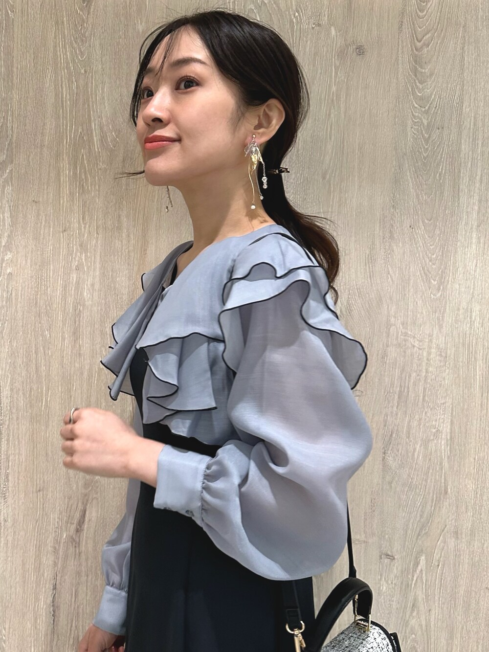 ブラック系のショルダーバッグ、グレー系のワンピース、ブラウン系のパンプスを着用したレディースの冬コーディネートの6枚目の写真