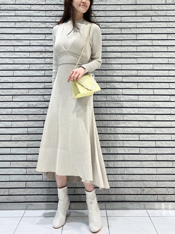 イエロー系のショルダーバッグ、ベージュ系のワンピース、ホワイト系のその他シューズを着用したレディースの冬コーディネートの2枚目の写真