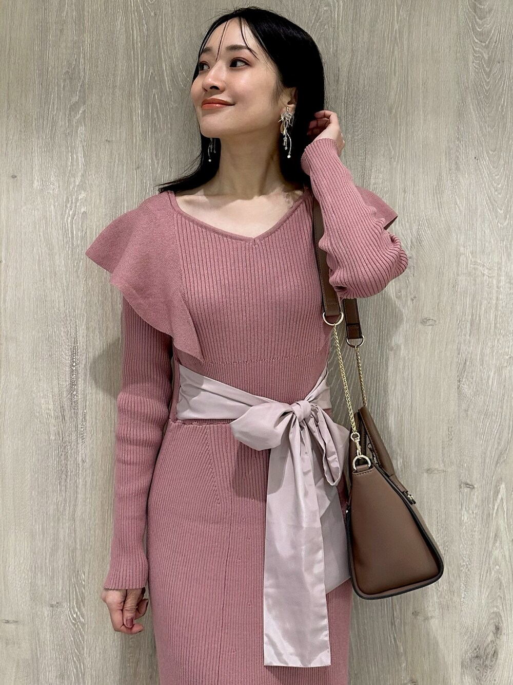 ピンク系のワンピース、ブラウン系のハンドバッグ、ブラウン系のブーツを着用したレディースの冬コーディネートの5枚目の写真