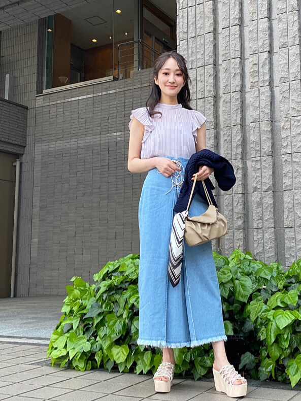 ベージュ系のクラッチバッグ、ホワイト系のサンダル、ブルー系のスカートを着用したレディースの春コーディネートの5枚目の写真